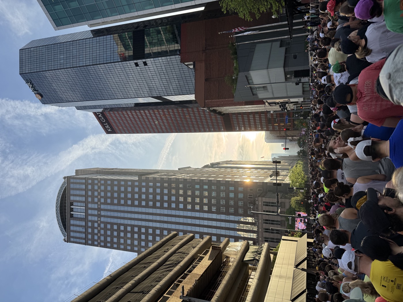 A crowd of runners filling a downtown Pittsburgh street at sunrise for a road race.